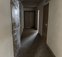 Folyosó egy családi házban, bézs burkolattal a padlón és műanyag ajtókkal.