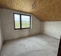 Kilátás egy családi ház üres szobájába tetőablakkal és betonpadlóval.