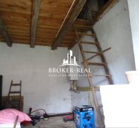 Családi ház belső tere fa mennyezettel és létrával, szerszámokkal és ládákkal berendezve.