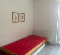 Garzonlakás ággyal, piros takaróval és fa dekorációjú padlóval.