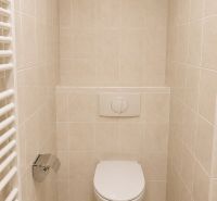 Fürdőszobai WC egy kétszobás lakásban, csempével és fali öblítőrendszerrel.