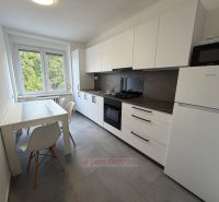 Konyha egy kétszobás lakásban világos étkezőasztallal és fehér szekrényekkel.