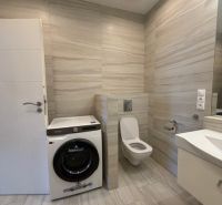 Fürdőszoba mosógéppel és WC-vel egy háromszobás lakásban, kőmintás csempékkel.