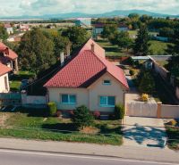 Családi ház Nadlicén kerttel és piros tetővel vidéken.