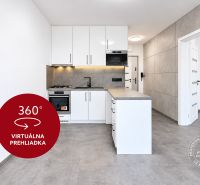 Konyha egy kétszobás lakásban fehér szekrényekkel és szürke padlóval.