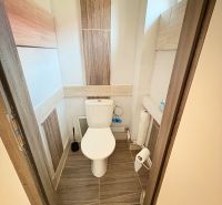 WC egy családi házban kerámia padlóval és keskeny ablakkal.