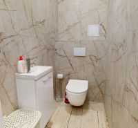 Fürdőszoba kétszobás lakásban WC-vel, mosdóval és márványburkolattal a falakon.