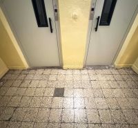 Csempézett folyosó két lifttel egy egyszobás lakásban.