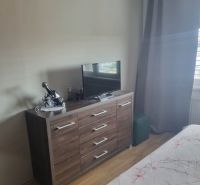 3 szobás lakás belső tere komóddal és televízióval, fa dekoros padlóval.