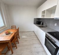 Konyha egy kétszobás lakásban fehér konyhabútorral és fa mintázatú padlóval.