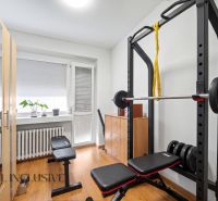 Családi ház edzőterme padokkal, súlyzókkal és fa dekorációjú padlóval.