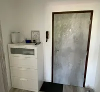 Előszoba fa mintázatú padlóval, cipősszekrény és ajtók egy kétszobás lakásban.
