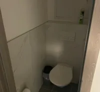 Csempeburkolatú és légfrissítővel ellátott WC egy kétszobás lakásban.