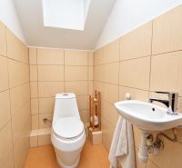 Fürdőszoba családi házban WC-vel és mosdóval, bézs csempék.
