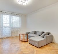 Nappali egy kétszobás lakásban, fa dekorációjú padlóval és szürke kanapéval.