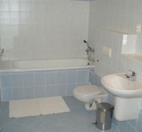 Fürdőszoba egy háromszobás lakásban káddal, mosdóval és WC-vel, kék-fehér csempékkel.