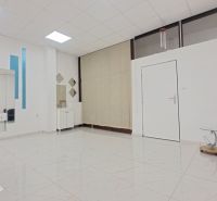 Üzlethelyiség belső tere székkel, tükrökkel és fehér mintás csempével.