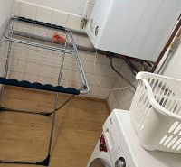 Mosókonyha családi házban mosógéppel, szárítóval és fa mintázatú padlóval.