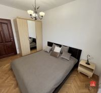 Hálószoba egy háromszobás lakásban franciaággyal és szekrénnyel, fa dekorációjú padlóval.