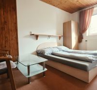 Nyaraló apartman hálószobája franciaággyal, székekkel és ablakkal, fa dekorációjú padlóval.
