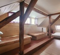 Tetőtéri szoba egy üdülő apartmanban fa dekorációjú padlóval és ágyakkal.