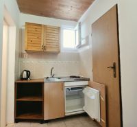 Konyhasarok a nyaraló apartmanban fa szekrényekkel, mosogatóval és minibárral.