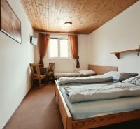 Hálószoba üdülő apartmanban két ággyal és TV-vel, fa dekoros padlóval.