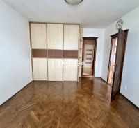 Szoba egy háromszobás lakásban fa dekoros padlóval és beépített szekrénnyel.