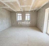 Tágas szoba egy családi házban nagy ablakokkal és betonpadlóval.