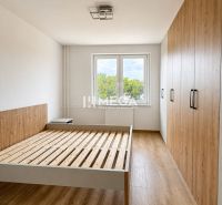 Hálószoba egy háromszobás lakásban fa dekor padlóval és beépített szekrénnyel.