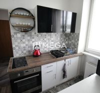 A nyaraló apartman konyhája fekete szekrényekkel, főzőlappal és dekoratív burkolattal.