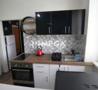 Konyha a nyaraló apartmanban fa dekor padlóval és geometrikus csempékkel a falon.