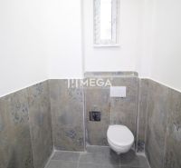 Egy egyszerűen kialakított, kereskedelmi helyiségben található fürdőszoba, amely WC-vel és keskeny ablakkal rendelkezik.