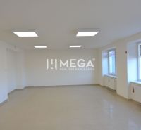 Világos üzlethelyiség nagy ablakokkal, csempével és mesterséges világítással.