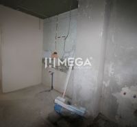 Befejezetlen belső tér egy családi házban betonpadlóval és radiátorcsatlakozással.