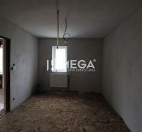 Sarokszoba egy családi házban betonpadlóval és csupasz falakkal.