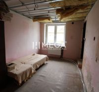 Családi ház berendezés nélküli belső tere ággyal és fedetlen mennyezettel.