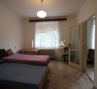 Hálószoba két ággyal és fa dekoros padlóval egy kétszobás lakásban.