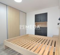 Hálószoba egy háromszobás lakásban, ággyal és tárolóhellyel sötét dekorációval.