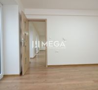 Szoba egy háromszobás lakásban, fa mintázatú padlóval és világos falakkal.
