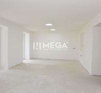 Kilátás egy üres szobára egy háromszobás lakásban, nagy ablakokkal és fehér falakkal.