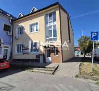Üzlethelyiségeket tartalmazó épület a szabadság téren, Humennéban, amely előtt parkolóhelyek találhatók.