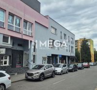 Üzletekkel és irodákkal rendelkező épületek a Felszabadítók utcában, Humenné, parkoló autók.