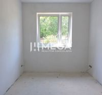 Üres szoba egy családi házban fehér falakkal és ablakkal.