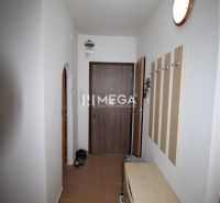 Kétszobás lakás folyosója fogasfallal, cipősszekrénnyel és barna csempével.