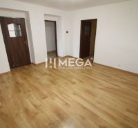 Egy üres szoba fehér falakkal és fa dekorációjú padlóval egy háromszobás lakásban.