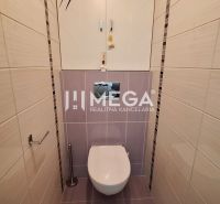 WC egy 3 szobás lakásban világos kerámia burkolattal és fali szekrénnyel.
