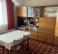 Ebédlő egy családi házban retro bútorokkal, szőnyeggel, csillárral, függönyökkel.