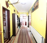 Egy családi ház folyosója radiátorral, szőnyegekkel és dekorációkkal a falakon.