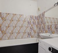Fürdőszoba káddal és mosógéppel egy háromszobás lakásban, feltűnő mintás csempékkel.